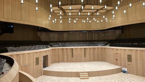 Der Konzertsaal des Casals Forums in Kronberg. Die Wände sind aus hellem Holz, von der Decke hängen schmale Lampen in Lichterketten-Optik. 