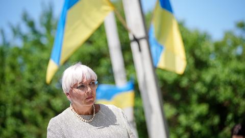 Weißhaarige frau, im Hintergrund mehrere ukrainische Flaggen.