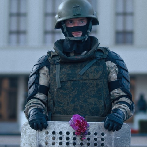Soldaten vor dem belarussischen Parlamentsgebäuse. Demonstranten haben ihm eine rote Blume ans Abwehrschild gesteckt.