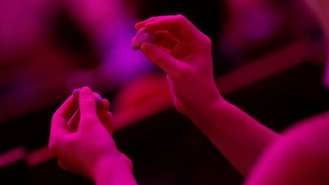 Zwei Hände in Nahaufnahme im pinkfarbenen Bühnenlicht
