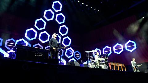 Drei Musiker auf der Bühne, im Hintergrund blau-weißes Licht