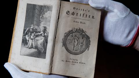 Nur mit Handschuhen darf ein Museumsmitarbeiter am 30.04.2014 im Museum Lottehaus in Wetzlar (Hessen) eine historische Ausgabe von "Goethes Schriften" aus dem Jahre 1787 aus der Vitrine nehmen