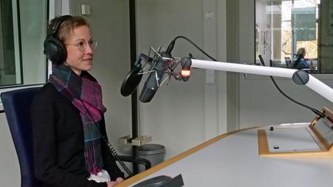 Jeanne Diesteldorf sitzt in einem Hörfunkstudio des hessischen Rundfunks und spricht ins Mikrofon