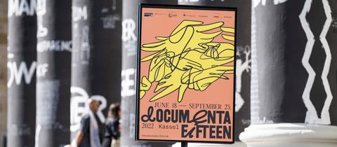 Ein Plakat der documenta in einem Plakatständer vor den Säulen des Museums Fridericianum.