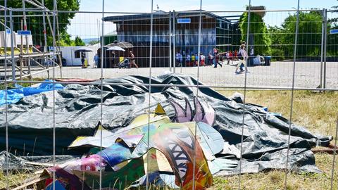 Reste einer Papp-Installation hinter einem Bauzaun. Im Hintergrund unscharf der Eingang zur documenta-Halle und Besucher davor.