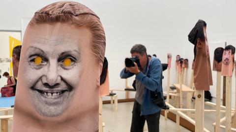 Eine Maske mit Foto ist über einen Holzstab gestülpt