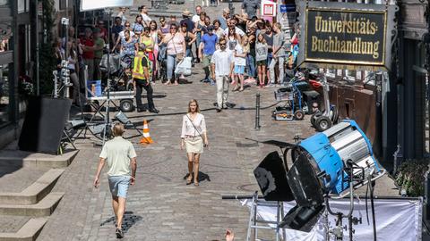 Eine Frau läuft in Marburg durch eine Gasse bei Dreharbeiten zum Conni 2, im Vordergrund steht ein großer Scheinwerfer