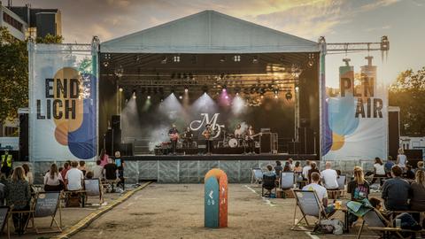 Szene vom Endlich Open Air in Darmstadt - 2021 ... Menschen sitzen in lockerer Anordnung in Liegestühlen vor einer Bühne.