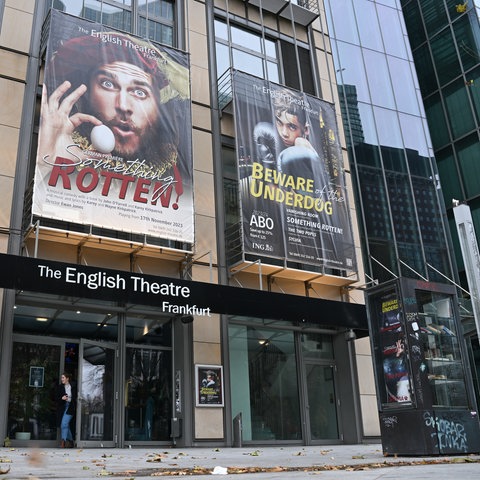 Auf einem Plakat über dem Eingang des Theaters wird das Musical "Something Rotten" beworben. 