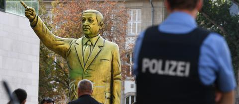 Passanten und Polizei stehen auf dem Platz der Deutschen Einheit vor einer goldenen Erdogan-Statue. 