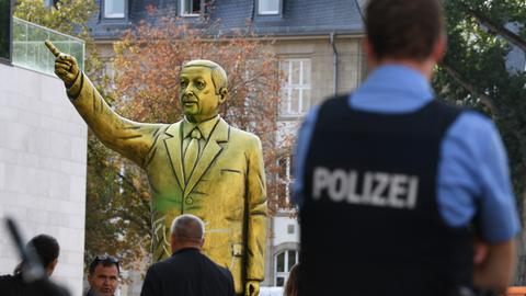 Passanten und Polizei stehen auf dem Platz der Deutschen Einheit vor einer goldenen Erdogan-Statue. 