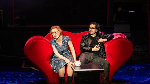 Eine Frau und ein Mann sitzen auf einem Sofa. 