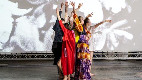Tänzerinnen in bunter Kleidung tanzen vor einer Video-Leinwand