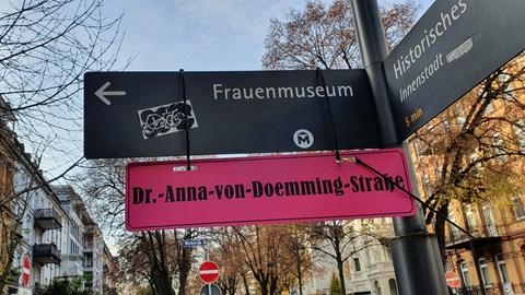 Unter einem Wegweiser mit der Aufschrift "Frauenmuseum" hängt ein rotes Schild mit der Aufschrift "Dr-Anna-von-Doemming-Straße".