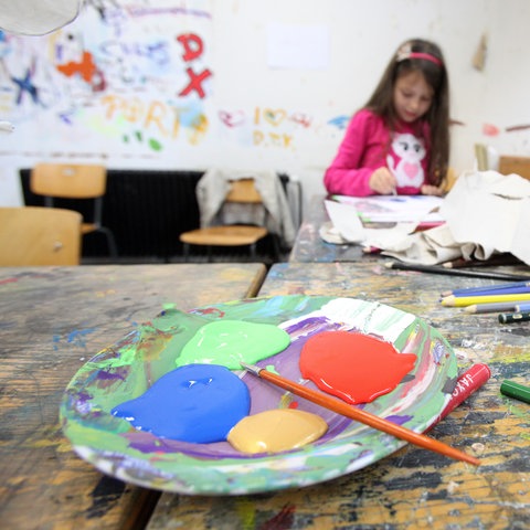 Kinder malen in einem Atelier, im Vordergrund eine Schale mit Farbe