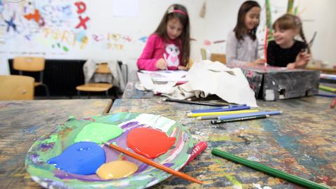 Kinder malen in einem Atelier, im Vordergrund eine Schale mit Farbe