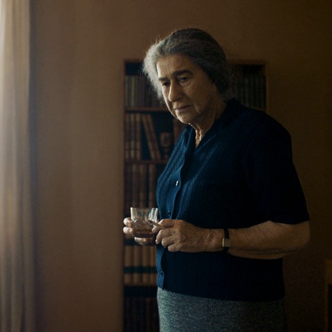 Ältere Frau mit einem Glas und einer Zigarette in der Hand