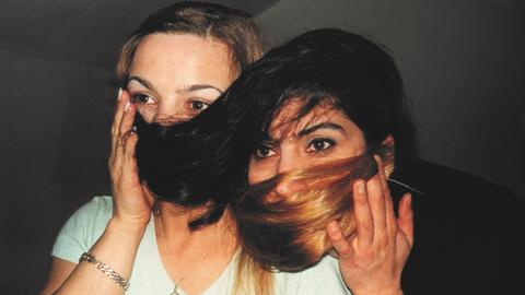 Zwei Frauen, die ihre Haare vors Gesicht halten
