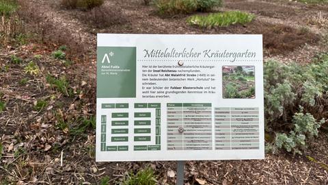 Ein Schild im Gartenbeet erklärt den mittelalterlichen Kräutergarten.