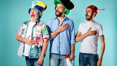 Drei verkleidete Fußball-Fans singen pathetisch