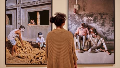 Eine Besucherin betrachtet zwei großformatige Fotografien, die Frau ist von hinten aufgenommen