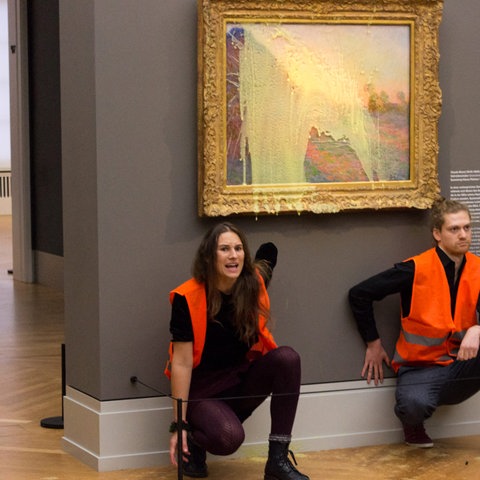 zwei Aktivisten kleben sich vor Gemälde im Museum fest