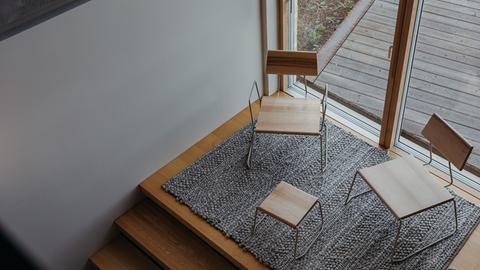 Two chairs and a side table of light wood and metal stand on a staircase.
