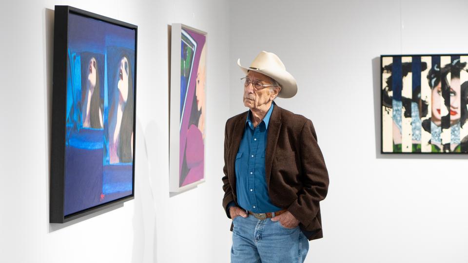 Maler James Francis Gill mit Cowboyhut vor zwei seiner Bilder