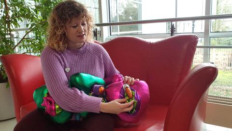 Mensch auf einem Sofa, zeigt auf bunte Stoff-Modelle