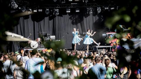 Zwei Frauen in hellblauen Kleidern auf einer Open Air Bühne