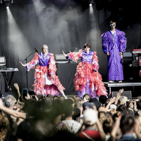 Drei Frauen in schrillen Kostümen auf einer Konzertbühne