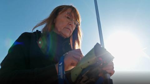 Frau mit Brille schaut auf ein Messgerät in ihrer Hand.