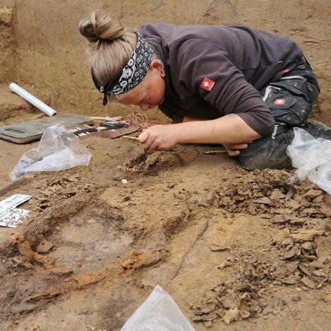 Eine Archäologin beim Freilegen eines Grabes