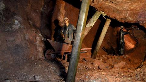 Eine lebensgroße Puppe mit Schubkarre in einem Bergwerk-Tunnel.