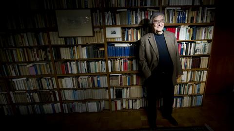 Peter Härtling vor einem Bücherregal in seiner Wohnung.
