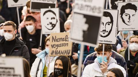 Bei einer Demonstration zum Gedenken an die Opfer des rechtsextremistischen Anschlags in Hanau halten Teilnehmer Plakate mit Bildern der Opfer des Anschlags.