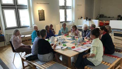 Mehrere Frauen sitzen um einen großen Tisch im Museum
