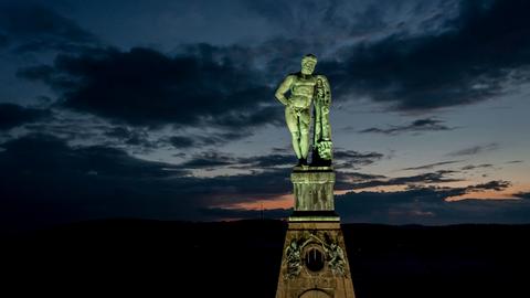Das Bild zeigt die beleuchtete Herkules-Statue im Bergpark Wilhelmshöhe in Kassel bei Nacht