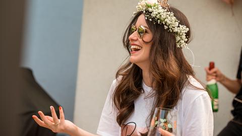 Junge Frau mit Blumenkranz und Sektglas