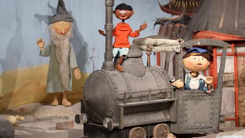 Die Marionetten "Tur Tur" (l-r), "Jim Knopf" und "Lukas" stehen zusammen mit der Lokomotive "Emma" im Puppentheatermuseum. 