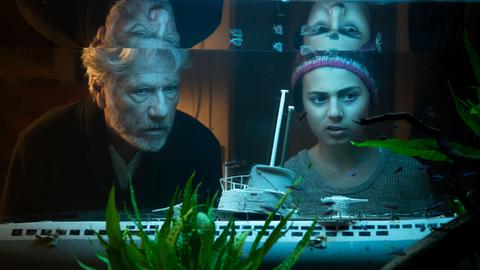 Filmstill "Eine Handvoll Wasser": Jürgen Prochnow und Milena Pribak alias Konrad und Thurba betrachten ein Aquarium.