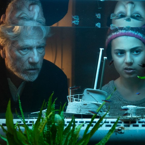 Filmstill "Eine Handvoll Wasser": Jürgen Prochnow und Milena Pribak alias Konrad und Thurba betrachten ein Aquarium.