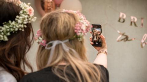Zwei Frauen mit Blumenkranz machen ein Selfie von sich.