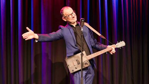 Kabarettist Severin Groebner mit Gitarre auf der Bühne