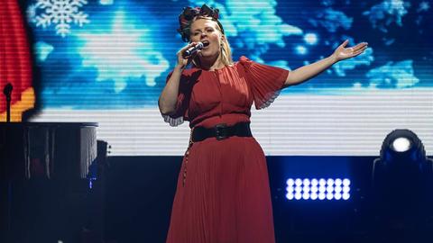 Frau in rotem Kleid steht auf der Bühne