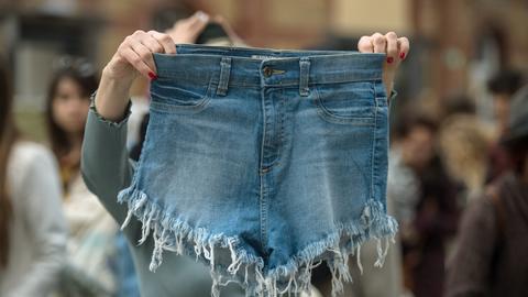 Eine Frau hält eine abgeschnittene Jeans hoch