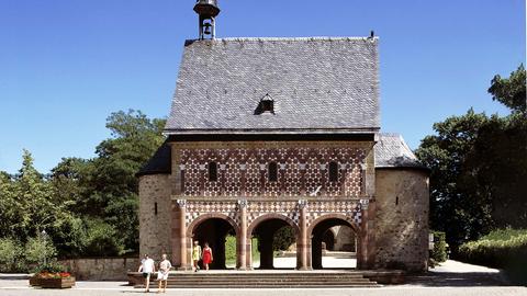 Ein historisches Bauwerk, umgeben von einem Park und Menschen, die es besichtigen.