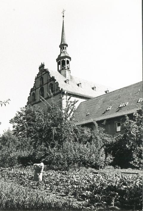 Historische Schwarz-weiss-Aufnahme: eine Nonne arbeitet im Garten.