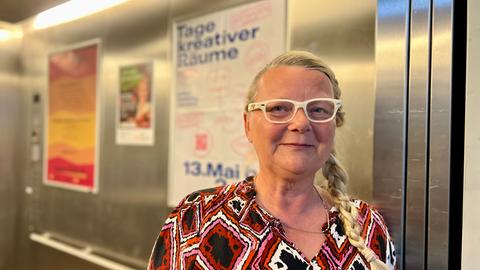 Frau mit weißer Brille im Fahrstuhl.