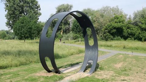 Eine Skulptur wie ein übergroßer Carrera-Bahn-Loop steht auf einer Wiese